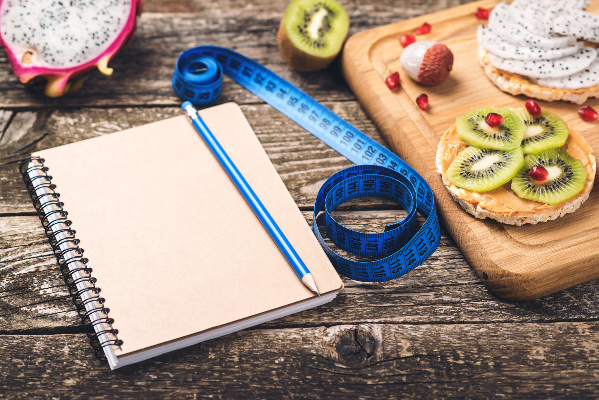 Toasts with fruit, measuring tape and empty notebook on wooden background. Slimming plan with fruits. Planning healthy diet concept. Healthy eating, dieting, slimming and weigh loss .